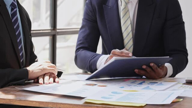 Young colleagues discuss business and analytical price charts using calculators and laptops to calculate financial, tax, accounting, statistics and analytical research ideas.