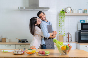 Smiling young couple cooking in kitchen.Playful cheerful biracial young couple kneading dough together on kitchen counter.Happy young couple cooking