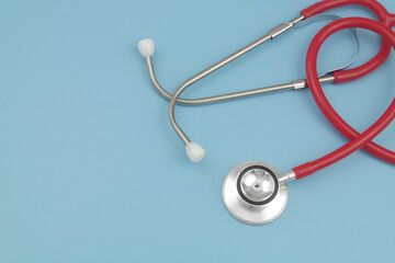 Red stethoscope on blue background with space for text.
