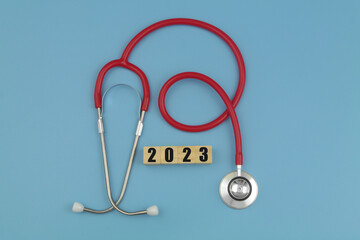 Red stethoscope with numbers 2023 on wooden cubes. Medicine in 2023 concept.