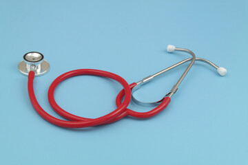 Red stethoscope on blue background close up. Medicine  and cardiology concept.