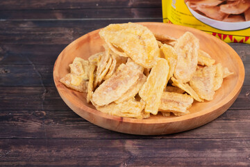 Banana chips with melted cheese flavor made from raw bananas fried on a wooden plate.