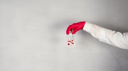 The doctor is holding a test tube with red viruses, bacteria and microbes.An antiviral drug search...