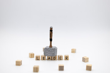 The hammer is standing on the wooden cubes with the word LEADER against white background