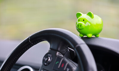 Green piggy bank money box inside car, vehicle purchase, insurance or driving and motoring cost - 598254380