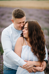 Man and woman standing and enjoys floral glade, summer nature. Loving couple walking at sunset. Family hugging in violet lavender field of flowers. France, Provence. Honeymoon trip, traveling. Closeup