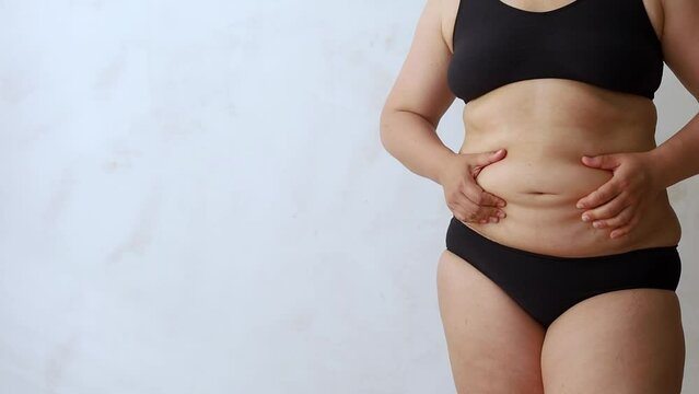 Unrecognizable buxom woman wearing black underwear, squeezing flabby fat of stomach with hands, doing massage on white background. Weight loss, lymphatic drainage, plastic surgery. Copy Generative AI
