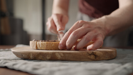 Man spreading chocolate cream on bread slice
