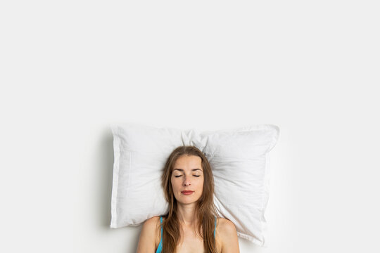 Sleeping young woman on a pillow on a white background. Top view, flat lay