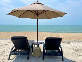 Beach lounge chairs under tent on beach with view of sea and blue sky .