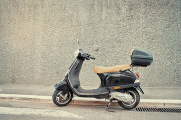 Motorbike outdoor. Black retro style scooter against grey wall.