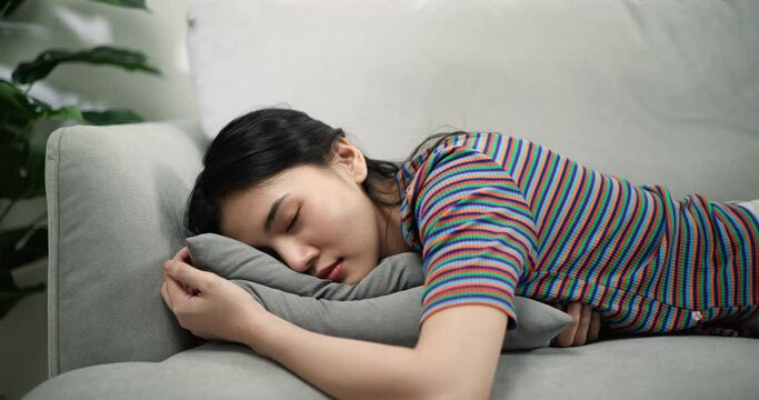 Slow motion shot of Exhausted woman asleep, Asian Young female closed her eyes and lay down on the cushions of the comfortable sofa with tired