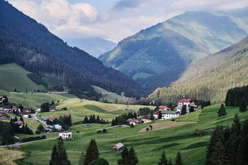 Fototapeta na wymiar Alpine mountains landscape. Village on green valley land.