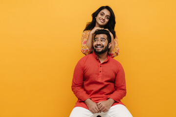 Indian man and woman posing isolated over yellow background