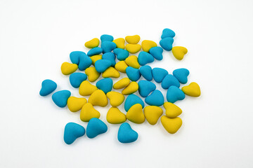 Bunch of yellow and blue heart-shaped candies (close-up) isolated on a white background. State symbols of Ukraine