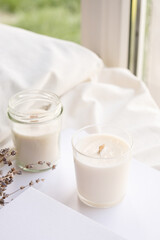 Soy wax aroma candles in jar on bed with lavender flowers. Candle mockup design