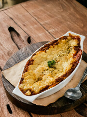 lasagna served in a white bowl, made with beef bolognese and bechamel sauce. text space
