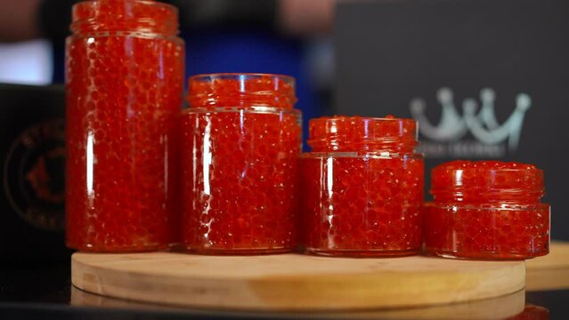 Close-up row of red salmon caviar in bottles of different size. Closeup tasty delicious delicatessen in kitchen indoors
