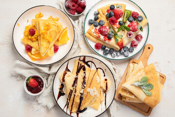 Sweet crepes assortment with berries chocolate on gray background. Homemade food concept. Top view,...