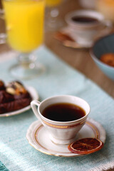 Plate of chocolate pralines, bowl of cookies, cups of tea, glasses of juice and lit candles on the table. Selective focus.