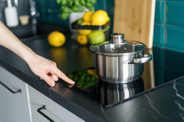 woman turn on electrical stove in modern kitchen