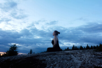 Young Woman Practicing Yoga In The Nature On The Sunset In A Rocky Area