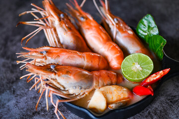 Shrimp soup on seafood soup bowl with thai herb and spices, Thai Food Tom Yum Kung, Hot and sour spicy shrimps prawns soup  curry lemon lime galangal red chili straw mushroom on table food