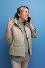 blond millennial woman talking on the phone on a blue isolated background