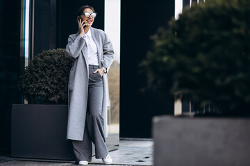 Business woman talking on the phone outside office bulding