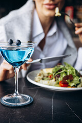 Woman drinking coctail and eating salad in a cafe