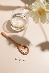 Pills in a wooden spoon. Glass of water. Women Health. Vitamins.