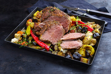 Traditional Greek barbecue leg of lamb with vegetable and feta cheese served as close-up on a...