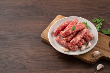 Raw Taiwanese sausage in garlic flavor in a plate on wooden table background.