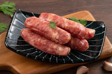 Raw Taiwanese sausage in garlic flavor in a plate on wooden table background.