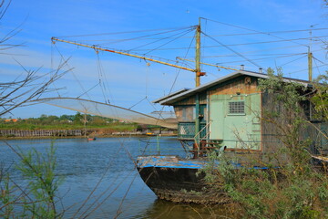 Fototapeta na wymiar An old mint-colored fishing hut, located on an old fishing boat in the Po Delta in Italy on a May afternoon.