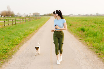 Woman and dog running and exercising outdoor at grass field on summer or spring. Happy female athlete training with her pet.