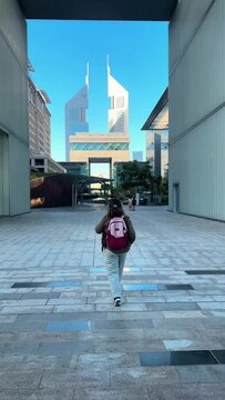 girl with a backpack goes forward rear view in a modern city. High quality FullHD footage