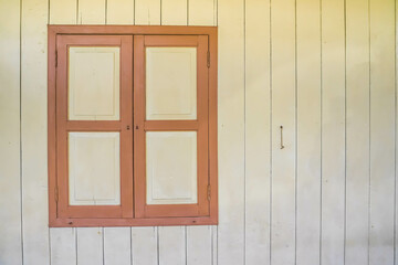 Obraz na płótnie Canvas Closed Old wooden window with shutters on an wooden wall. Window on indonesian malay traditional house. Sumatran traditional house. Empty Blank Text Space.