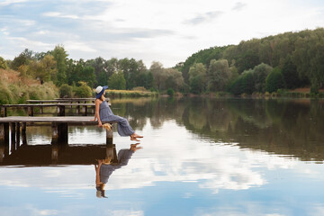 mother and daughter walk on the bridge by the water, girl in a hat on a wooden bridge, walk by the pond, pond, family near the lake 