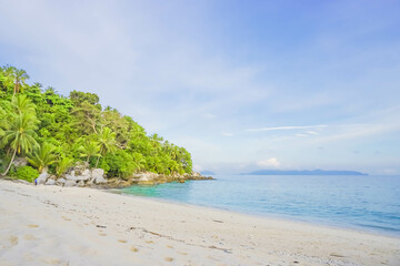 Obraz premium Durai Island, Anambas, Tropical beach with rocks, coconut trees, and blue sky with clouds on Sunny day. Summer tropical landscape, panoramic view. travel tourism panorama background concept.