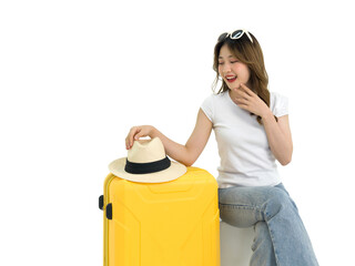 Young Asian woman wearing a white t-shirt and jeans picking up a straw hat on a yellow suitcase. ...