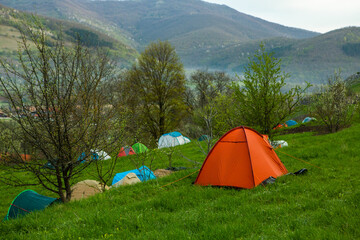 Camping tents on a green meadow in the mountains in spring. Rest with the tent in nature