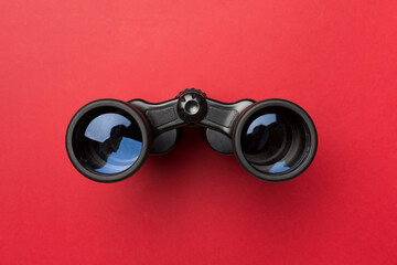Black binoculars on color background. Top view