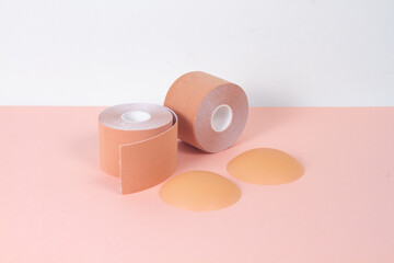 A pair of silicone sticker pad to cover nipples and Nude Boob Tape for woman on pink background