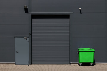 Industrial building with rolling gate for loading dock and large waste container.