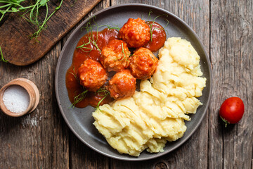 Mashed potatoes with meatballs in tomato sauce in a bowl