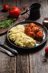 Mashed potatoes with meatballs in tomato sauce in a bowl