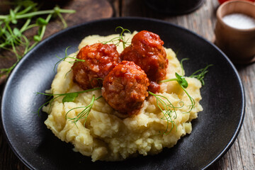 Fototapeta na wymiar Mashed potatoes with meatballs in tomato sauce in a bowl