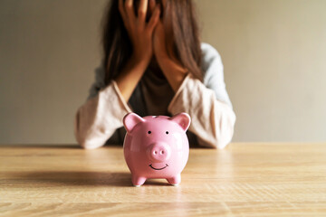 Sad girl with a piggy bank at home.