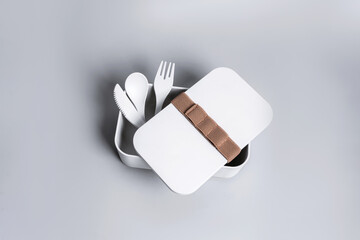 A set of white cutlery made of plastic and paper on the gray background. Eco, environmental conservation concept. Isolated reusable tableware. High quality photo.